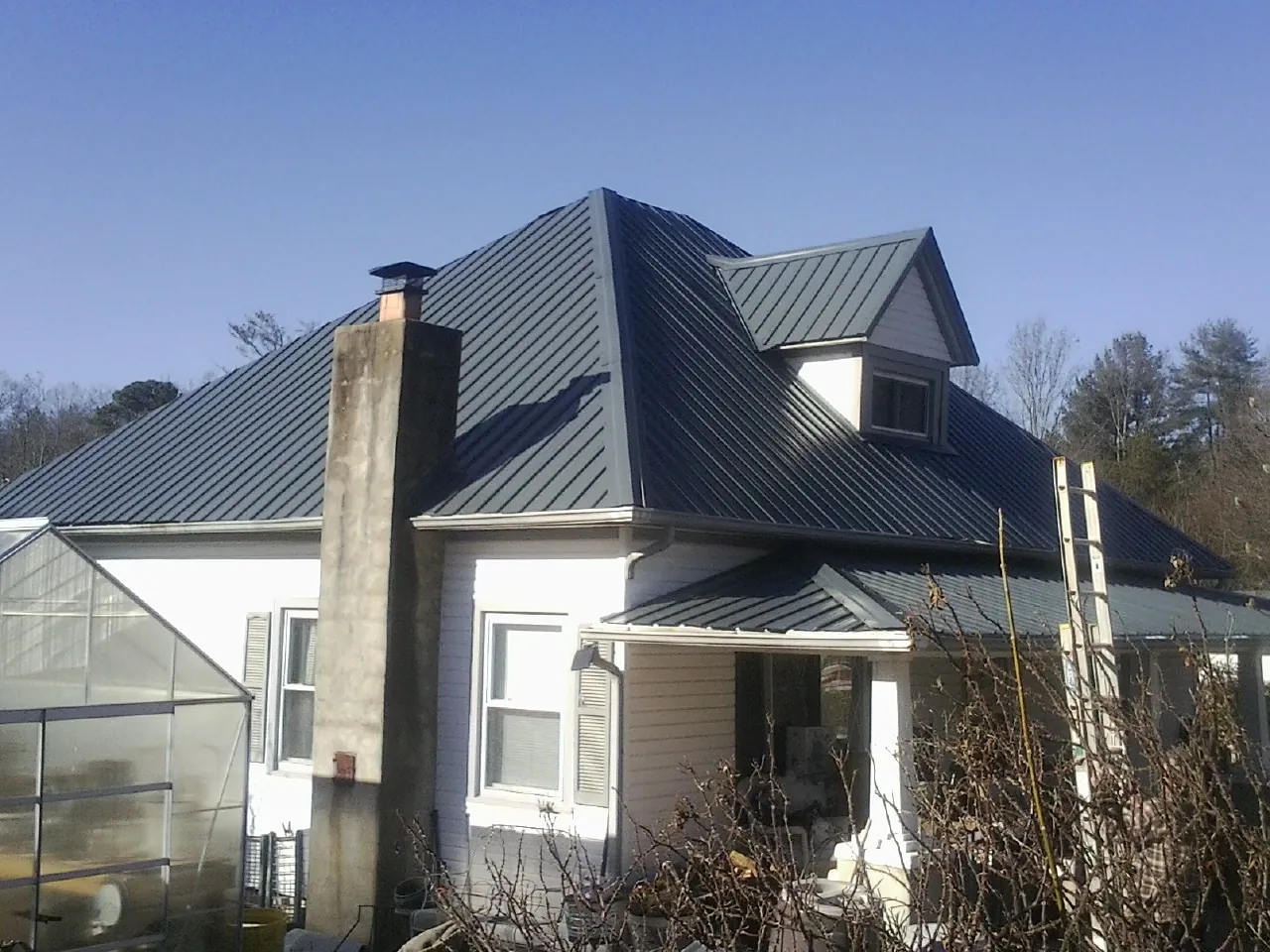 Dark blue standing seam metal roof on a white farmhouse with dormer — Slate & Tile Roof Repair by Roofing Brothers in Willow Springs