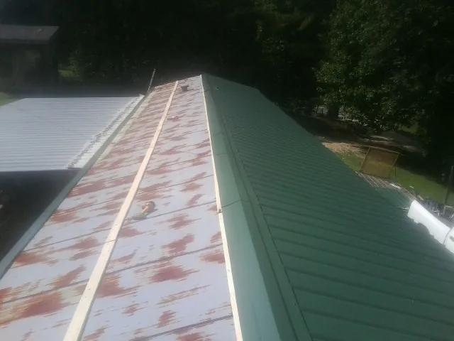 Old rusted panels beside newly installed green metal roofing — Wind Damage Roof Repair by Roofing Brothers in Willow Springs