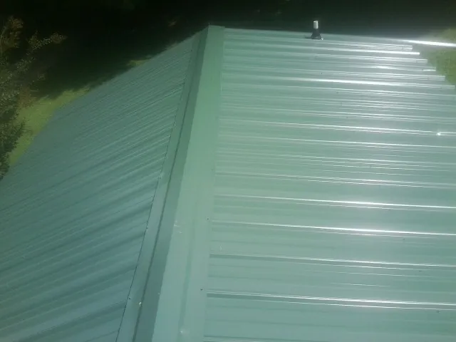 New green metal panels meeting at the ridge of a roof — Flat Roof Repair work by our crew in Willow Springs