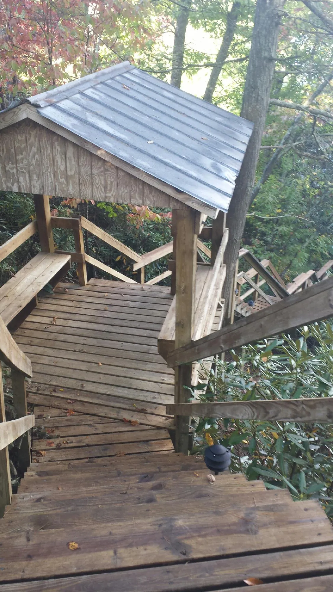 Metal roofed shelter over wooden steps on a wooded walkway — Skylight Repair & Installation work by our crew in Willow Springs