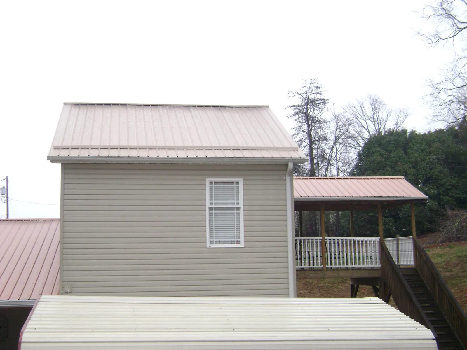Tan metal roofs on a two story addition and attached porch, from a Roof Replacement job in Willow Springs