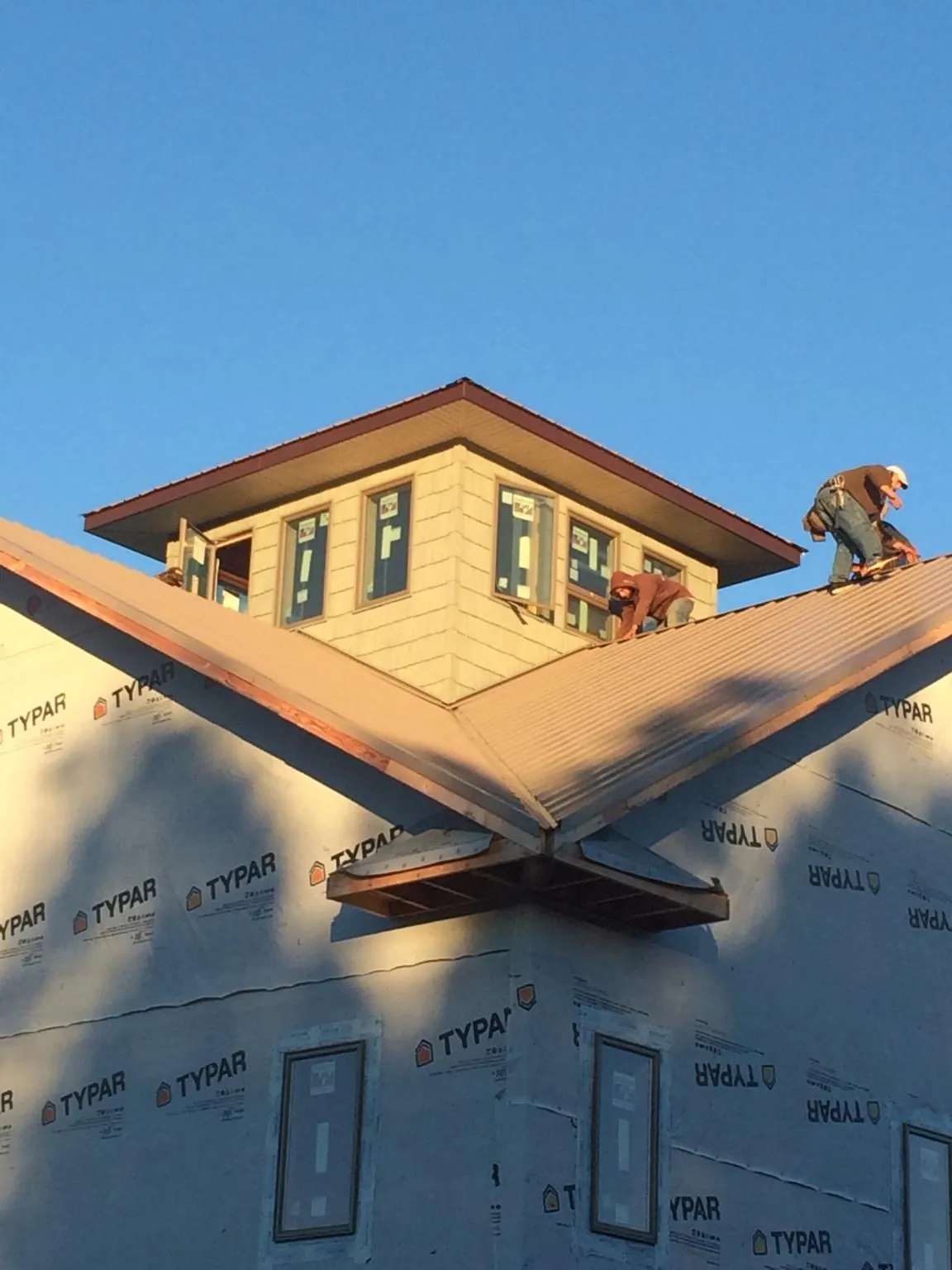 Roofers working around a rooftop cupola on a new metal roof at sunset — Roof Waterproofing in Willow Springs by Roofing Brothers